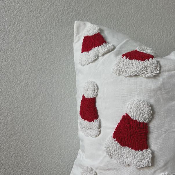 Decorative pillow with red and white Santa hat patterns on a plain background