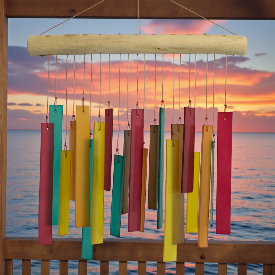 Colorful wind chimes hanging against a sunset over water backdrop